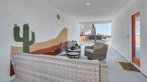 Un interior moderno con un mural de cactus, mobiliario de mimbre y vistas al exterior.