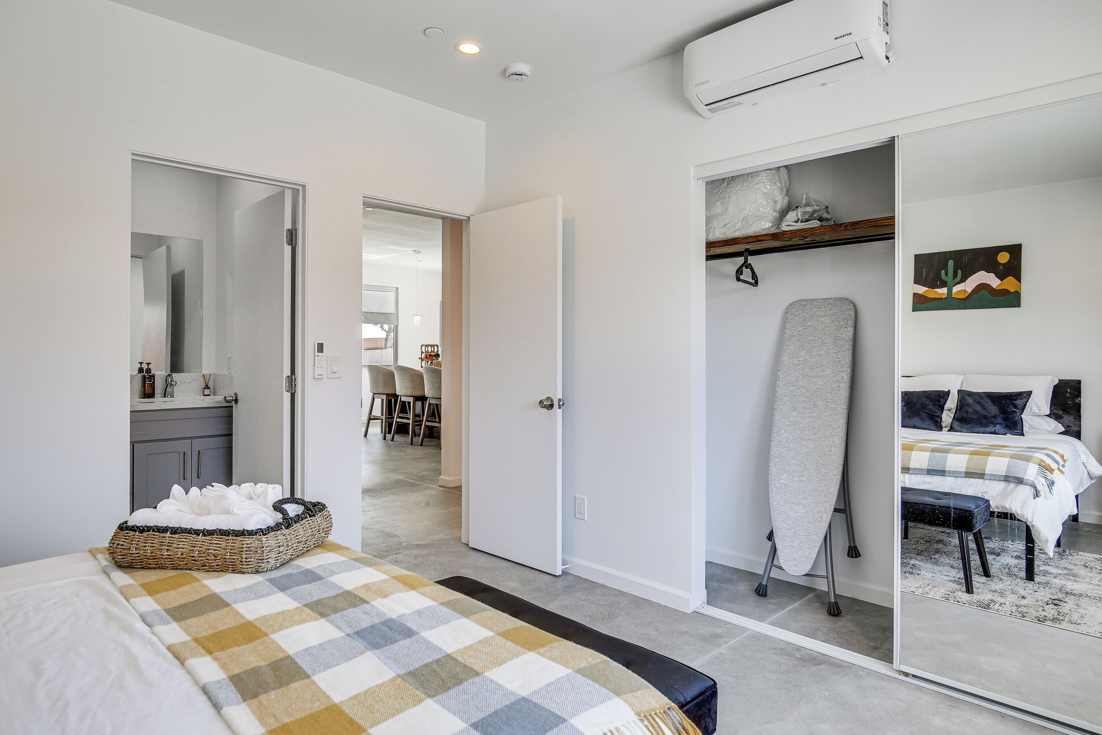 Een slaapkamer met een bed, een kledingkast, een spiegel en een prikbord.