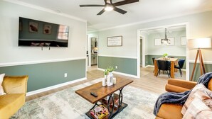 A living room with a TV, a ceiling fan, a dining area with a table and chairs, and a kitchen in the background. - 5 Mi to Fort Gregg-adams: Spacious Family Home (Colonial Heights)