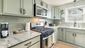 A kitchen with light green cabinets, a stainless steel microwave, a gas stove, and a coffee maker. - 5 Mi to Fort Gregg-adams: Spacious Family Home (Colonial Heights)