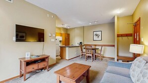 Um espaço compacto com cozinha compacta, área de refeições e sala de estar com sofá e mesa de centro.