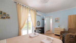 Um quarto com cama, escrivaninha, cadeira e cômoda.