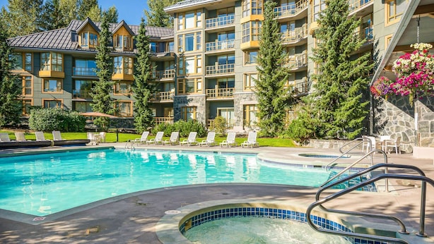 Un hôtel doté d’une piscine, de nombreux balcons et d’une façade en pierre.