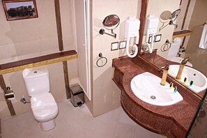 Un bagno con il water, un lavandino con uno specchio e un cestino.