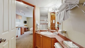 Une salle de bain d’hôtel avec un lavabo, un miroir, un porte-serviettes et une zone de douche visible au fond.