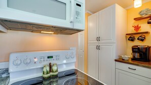 A kitchen with a white stove, microwave, and cabinets. - Relax Poolside: Couples Retreat 3 Mi to Gulf! (Fort Myers Beach)