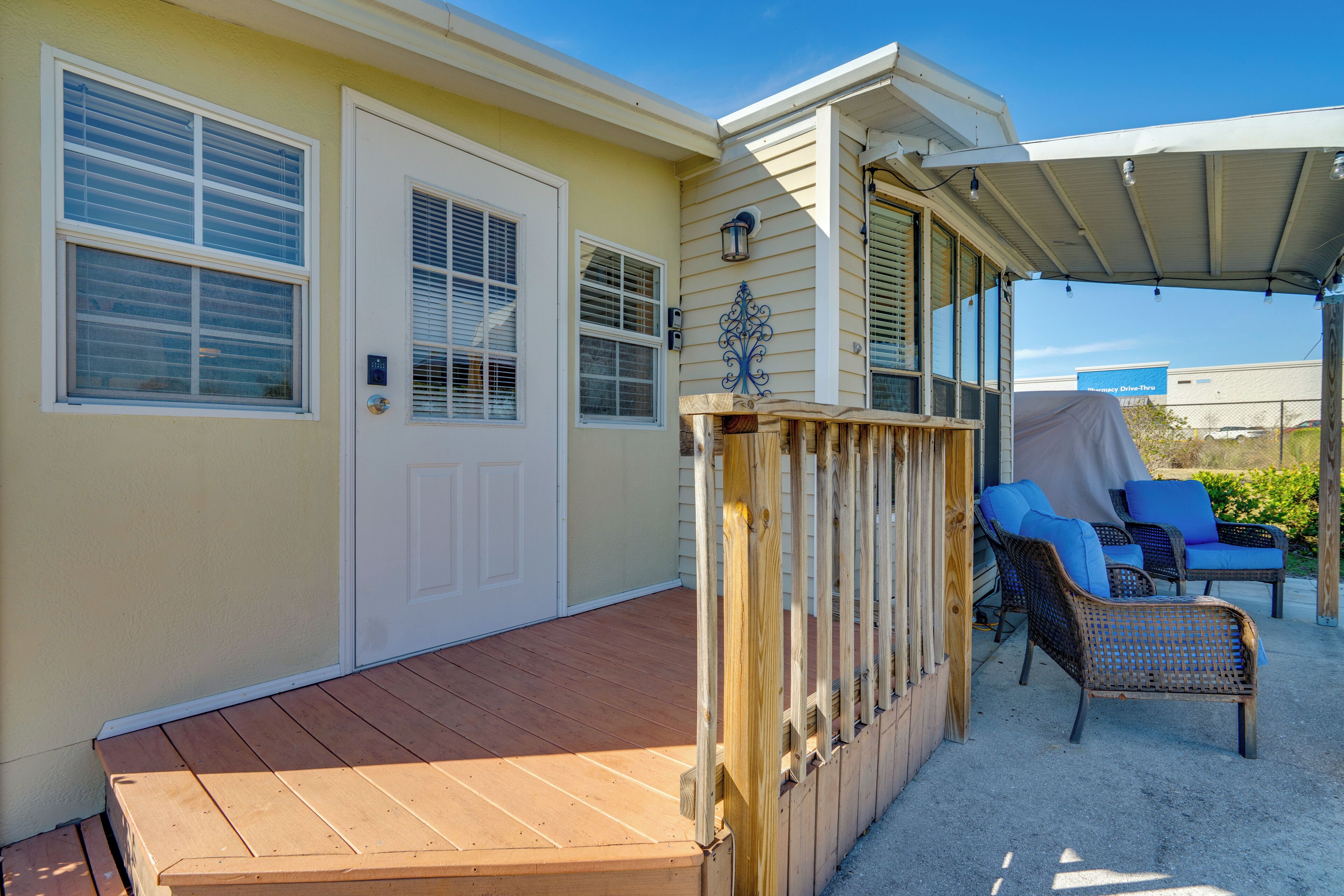 A covered deck with outdoor furniture, a door, and a window with blinds.