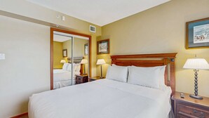 Une chambre d’hôtel avec un grand lit, des lampes de chevet, une table de chevet, un miroir et un tableau encadré au mur.