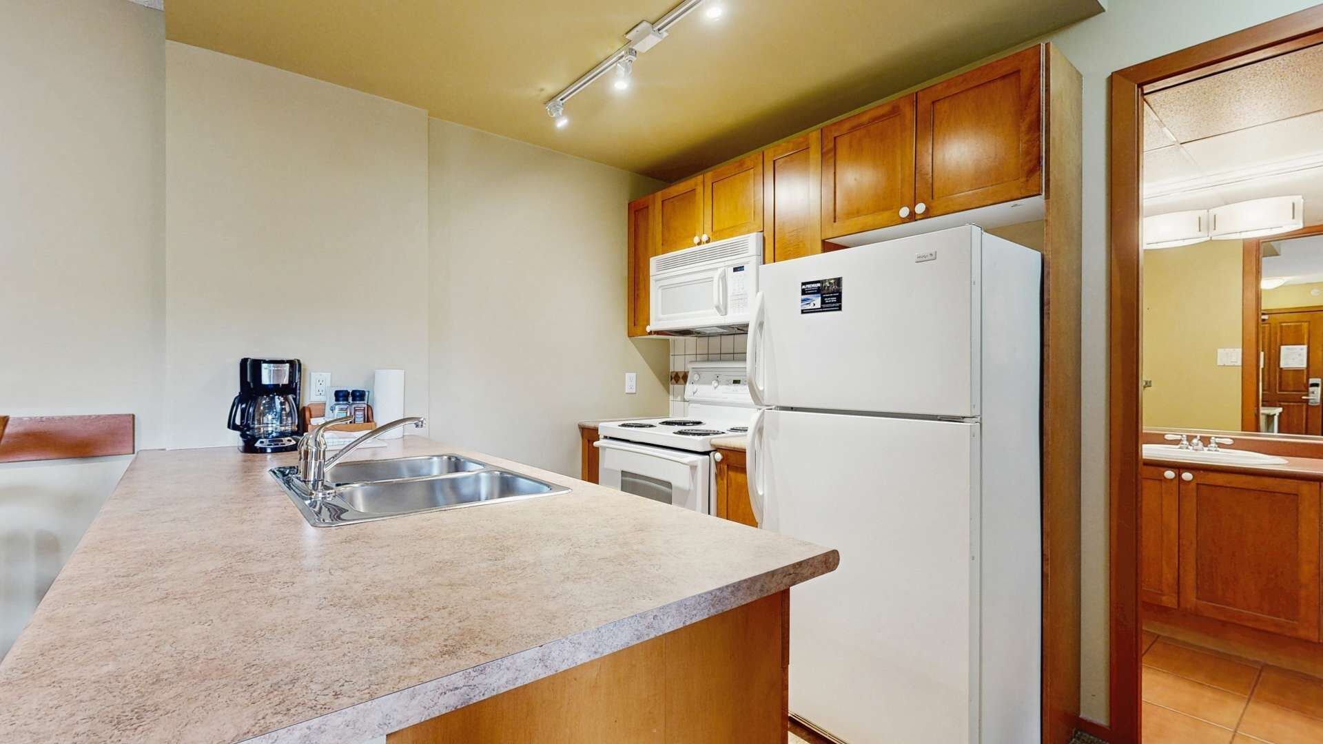 A compact kitchen with a sink, stove, microwave, and refrigerator.