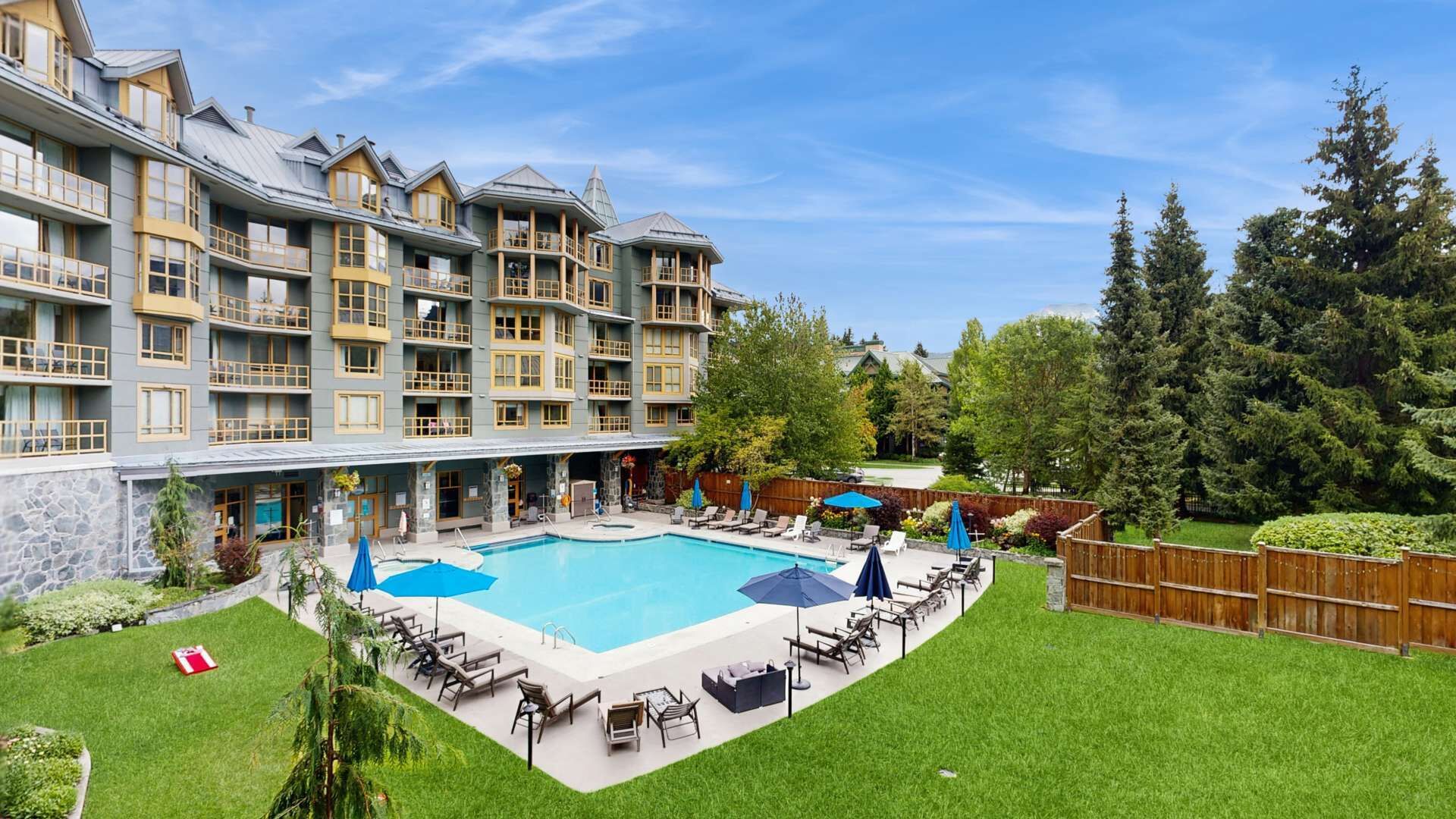 Een hotel met een zwembad, terras en een gevel van natuursteen.