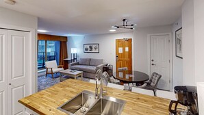 A compact living space with a kitchenette, a sofa, a dining table, and a view of the city. - Whistler - Cascade Lodge 232 (Whistler)