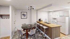 A modern kitchen with a central island, white cabinetry, and a dining area with a round table and chairs. - Whistler - Cascade Lodge 232 (Whistler)