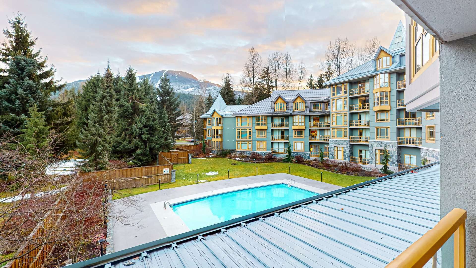 A hotel with a pool, surrounded by mountains and trees.