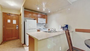 Una cocina compacta con armarios de madera, un refrigerador blanco, un microondas y una estufa.