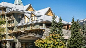 Un edificio de varios pisos con balcones y fachada de piedra, identificado como "Cascade Lodge".