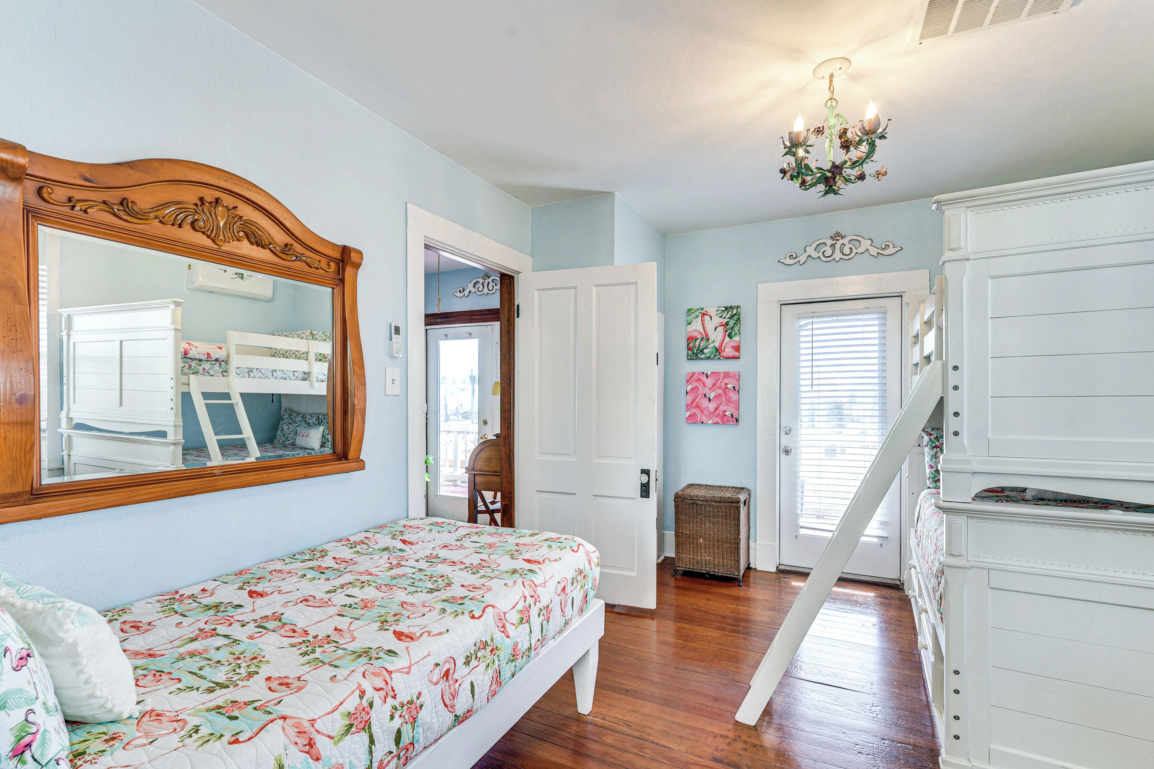 A bedroom with a bed, a dresser, a mirror, and a door leading to another room.