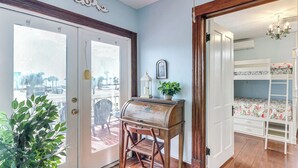 A room with a wooden desk, a chair, a window with a view, a bunk bed, and a chandelier. - Steps to Pleasure Pier: Family Escape w/ Pool! (Galveston)