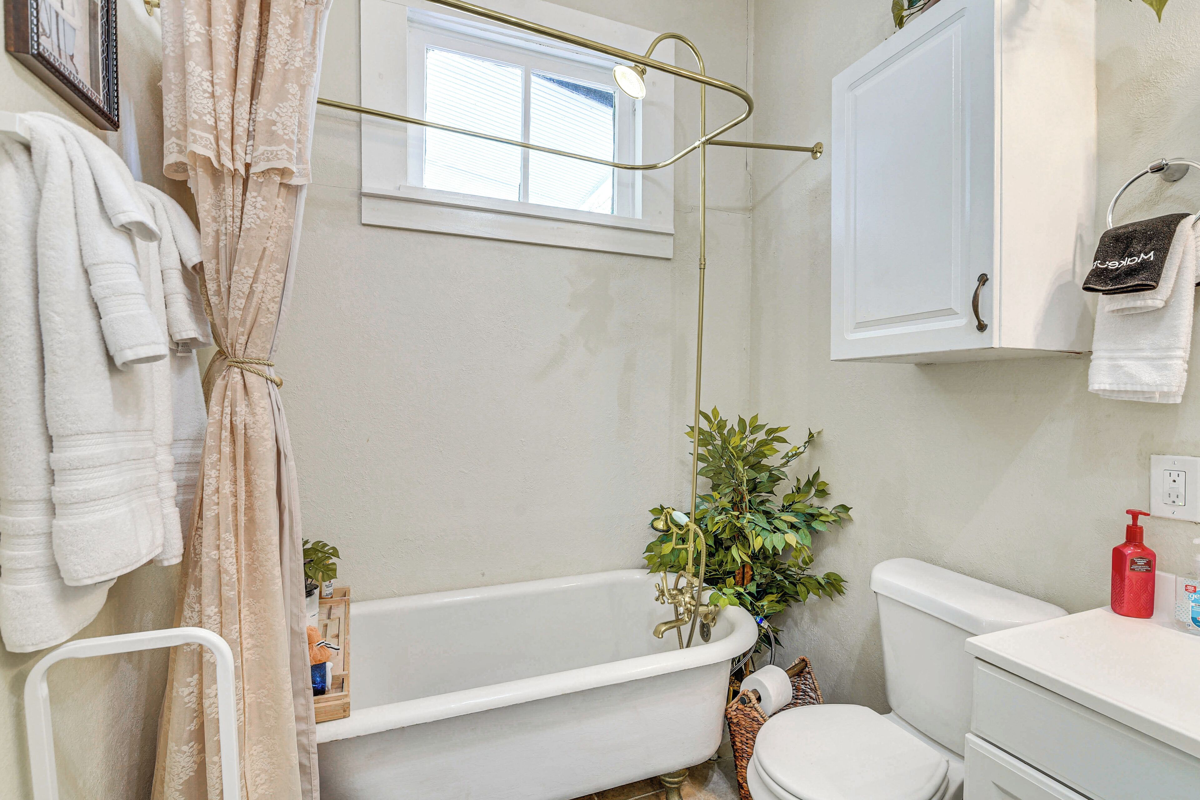 A bathroom with a bathtub, a toilet, a window, and a towel rack.