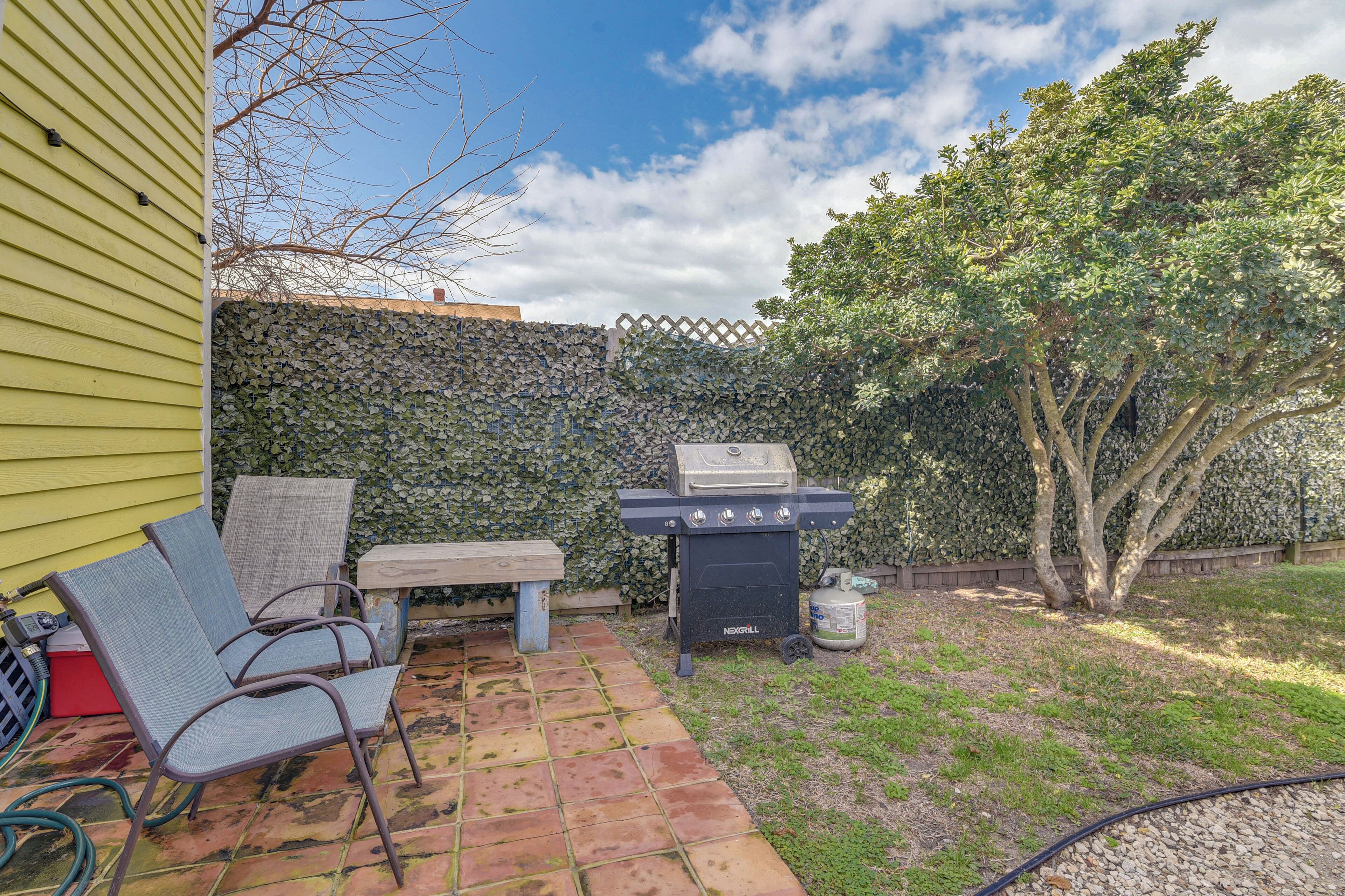 Un cortile con un barbecue, sedie e un tavolo.