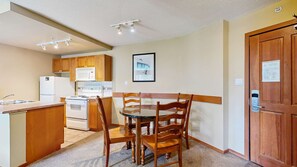 Una cocina compacta con armarios de madera, un refrigerador, estufa y un comedor con mesa y sillas.