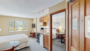 Une chambre d’hôtel de taille réduite comprenant un lit, une petite kitchenette, un coin repas et une salle de bain.