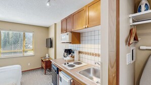 Une cuisine compacte avec des meubles en bois, un four à micro-ondes, une cuisinière et un évier.