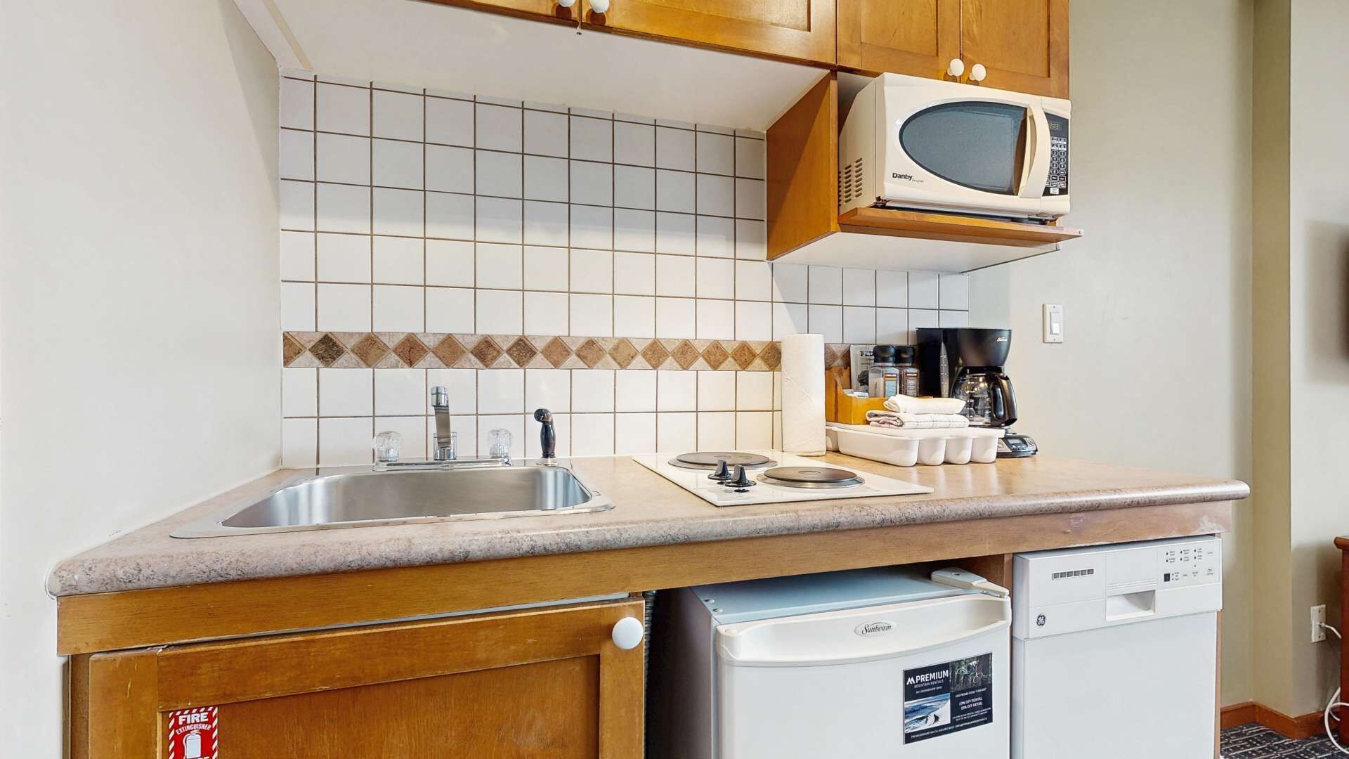 A kitchen with a double sink, a microwave, a coffee maker, and a dishwasher.