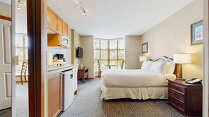 Une chambre d’hôtel équipée d’un lit, d’un bureau, d’une chaise, d’une télévision et d’une fenêtre avec des stores.