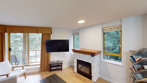 Ein Wohnzimmer mit Kamin, einem an der Wand befestigten Fernseher und einem Bücherregal.