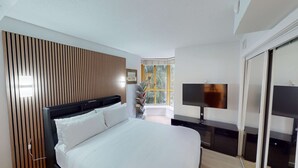 Ein modernes Hotelzimmer mit einem großen Bett, einem Nachttisch mit Flachbildfernseher, einem Holzschrankbett, einem Fenster mit Blick auf Bäume und einer eingebauten Bücherreolen.