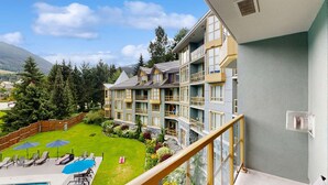 Ein mehrstöckiges Hotel mit Balkonen, einem Swimmingpool und einem gepflegten Garten.