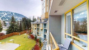 Un immeuble à plusieurs étages doté de balcons, d’un petit jardin et offrant une vue sur la montagne.