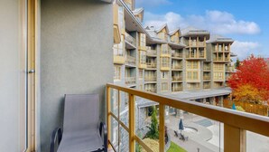 Ein Balkon mit Blick auf ein mehrstöckiges Gebäude mit Balkonen und eine angelegte Grünfläche darunter.