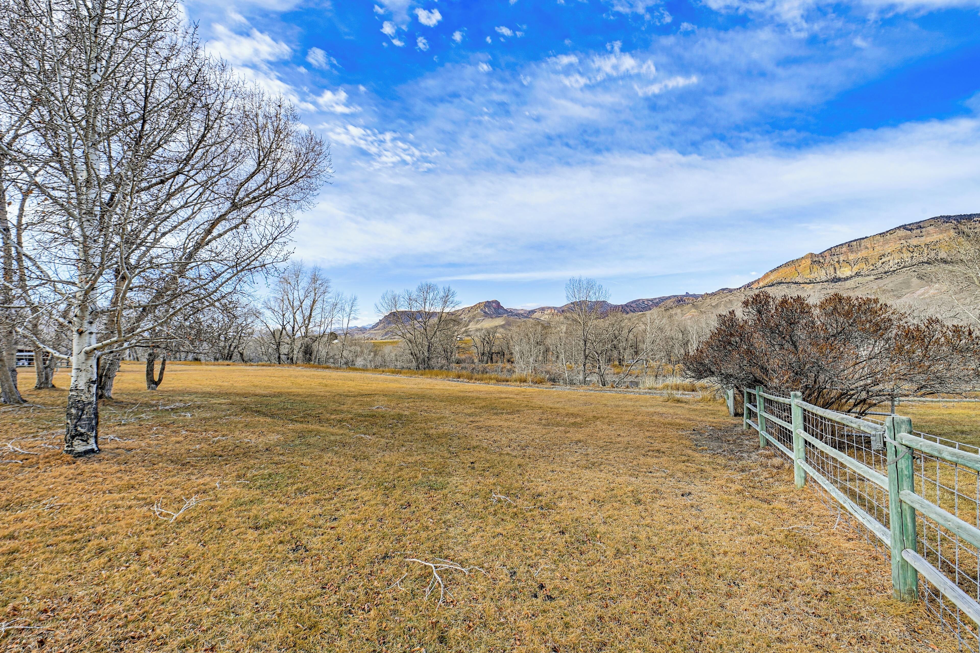 A fenced field with a tree and a mountain range in the background.