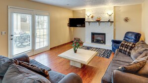 A living room with a fireplace, a sofa, a coffee table, and a TV mounted on the wall. - Bring the Family! Suburban Home w/ Yard in Omaha (Omaha)