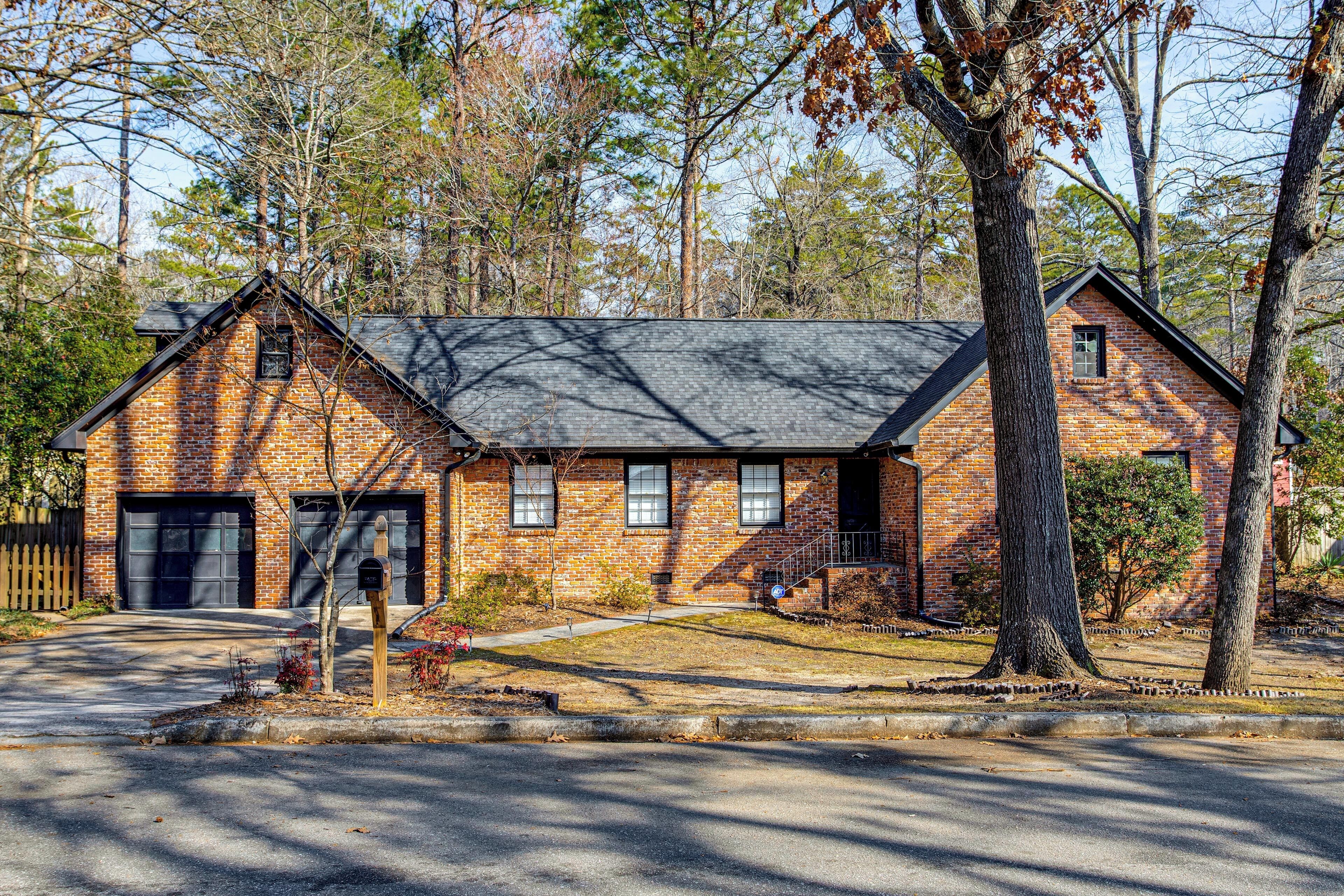 A brick house with a garage, a front yard, and a driveway.