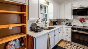 A kitchen with white cabinets, a stainless steel sink, a built-in oven, and wooden shelves. - Lake Murray Retreat Near USC & Columbia (Columbia)
