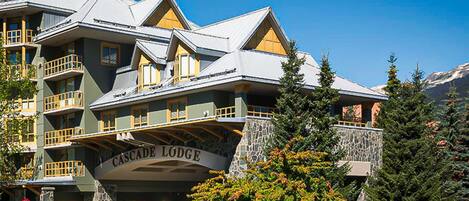 A multi-story building with balconies and a stone facade, labeled "Cascade Lodge."