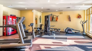 Ein Fitnessstudio mit Cardiogeräten, Gewichten und einem Coca-Cola-Automaten.