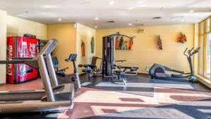 Ein Fitnessstudio mit Cardiogeräten, Gewichten und einem Coca-Cola-Automaten.