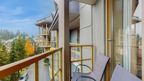 Ein Balkon mit Blick auf ein Wohngebiet, ein Stuhl und ein Fenster mit Blick auf ein Auto auf der Straße.