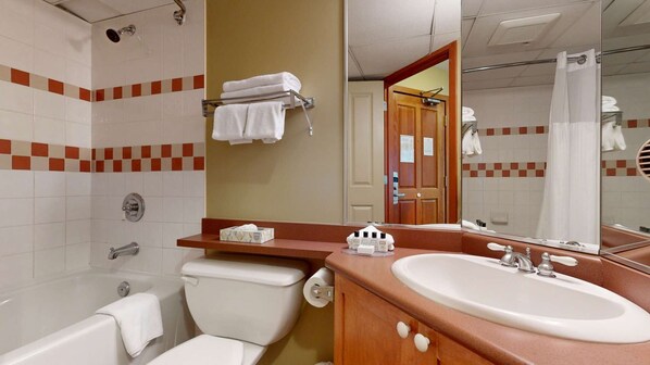 Une salle de bain comprenant une baignoire, des toilettes, un lavabo et un espace douche.