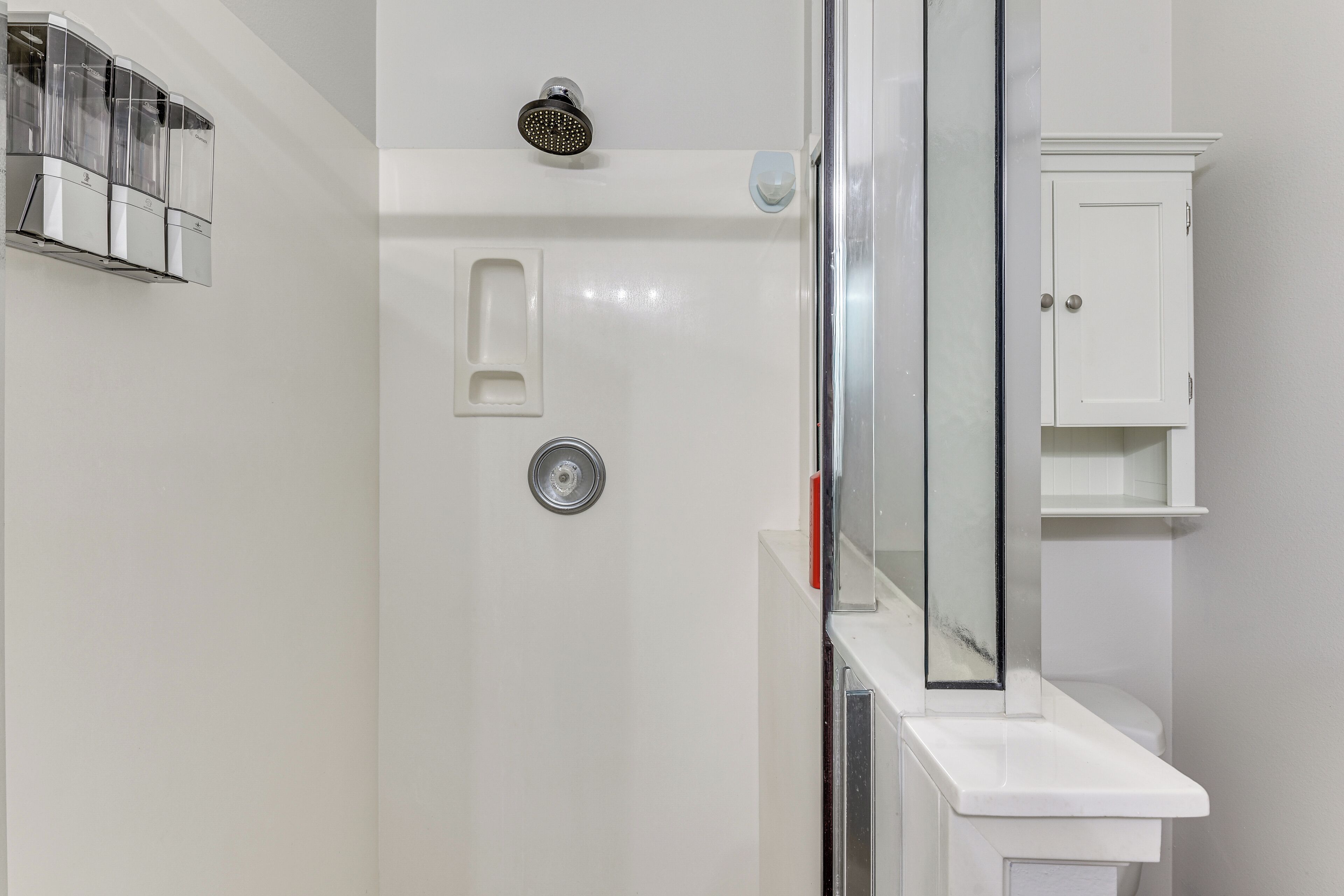 A modern bathroom with a glass shower enclosure, a white sink, and a cabinet.