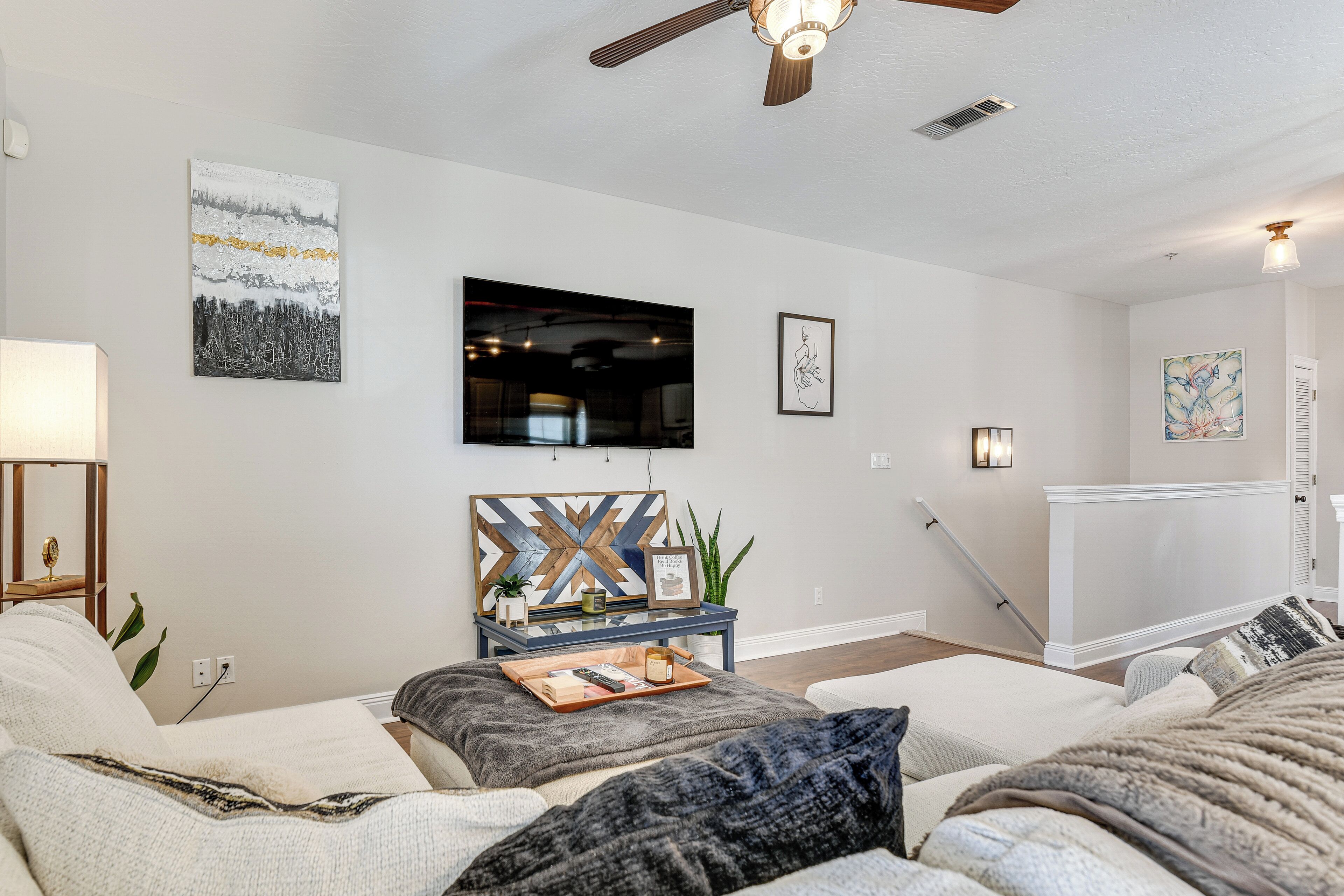 A modern living room with a sofa, a coffee table with a tray, and a TV mounted on the wall.