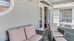 A covered porch with wicker furniture and a white exterior wall. - Walkable Dtwn Fort Walton Beach Condo w/ Balcony! (Fort Walton Beach)
