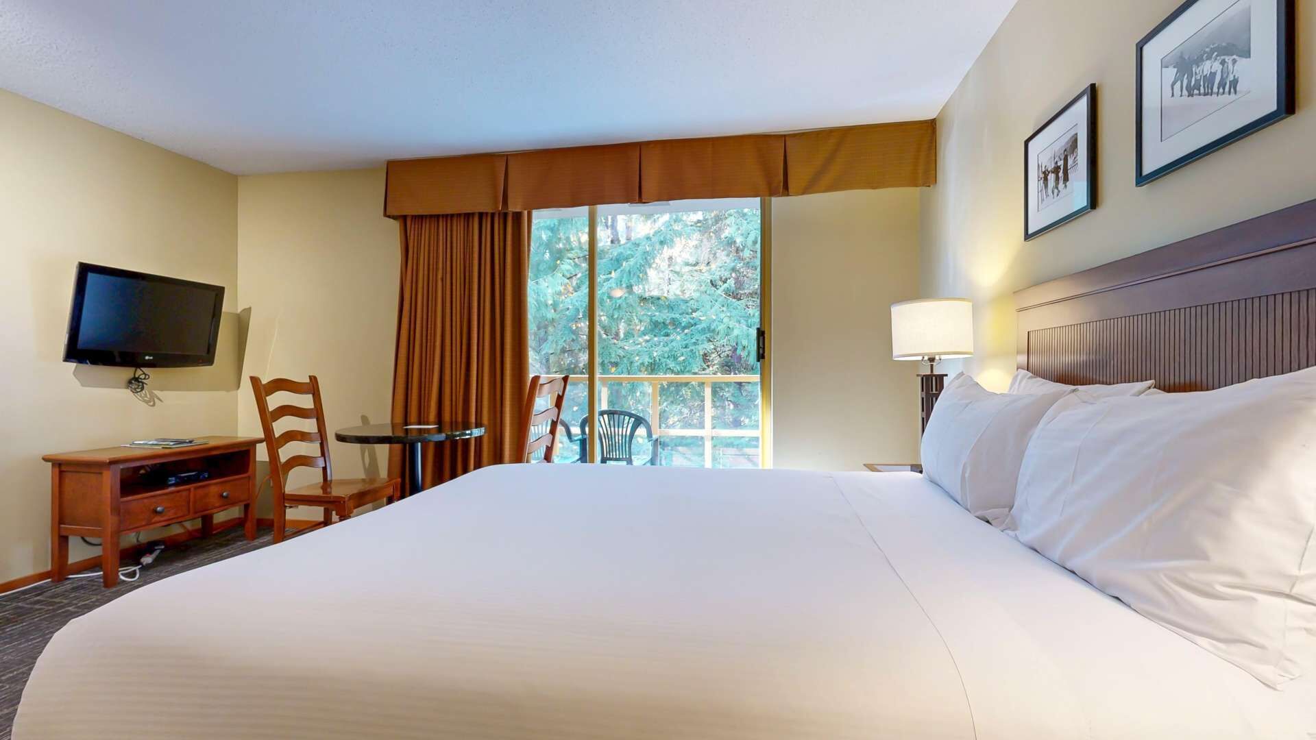 Une chambre d’hôtel avec un grand lit, une télévision, un bureau avec une chaise, une fenêtre avec des rideaux et une lampe.