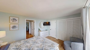 A bedroom with a bed, a dresser, a TV, and a closet. - Villa 506 2 bedroom, 1.5 bathroom (Jekyll Island)
