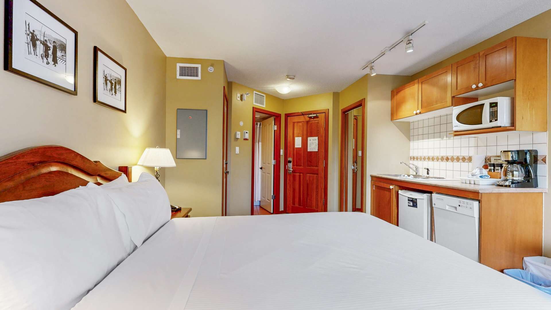 Une chambre d’hôtel équipée d’un lit, d’un bureau, d’un four à micro-ondes et d’une petite kitchenette.
