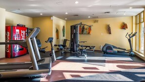 Ett gym med konditionsmaskiner, styrketräningsmaskiner och ett väggmonterat ställ.