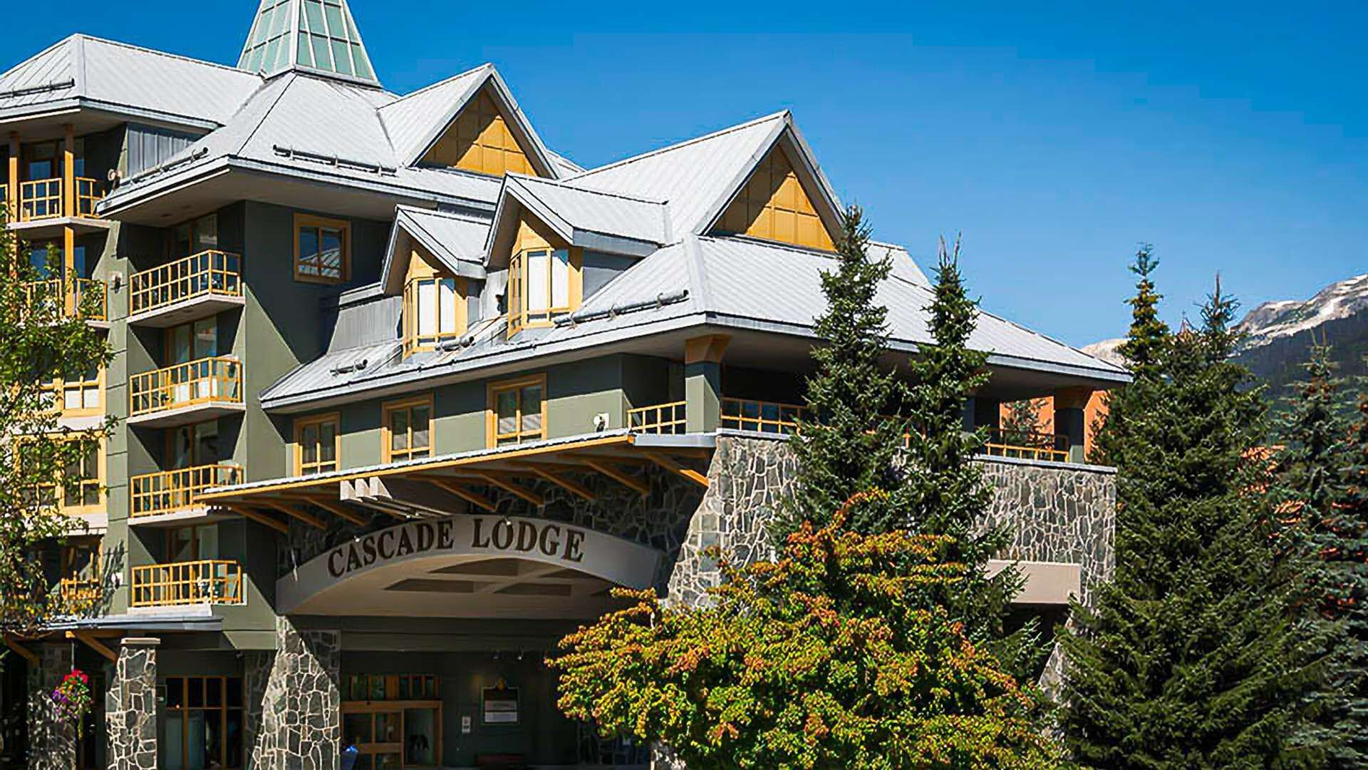 Un edificio de varios pisos con balcones y fachada de piedra, con el letrero "Cascade Lodge".